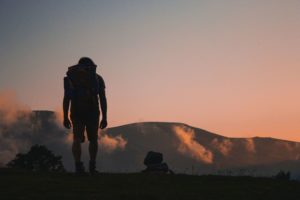 Homem andando na montanha com um mochilão nas costas